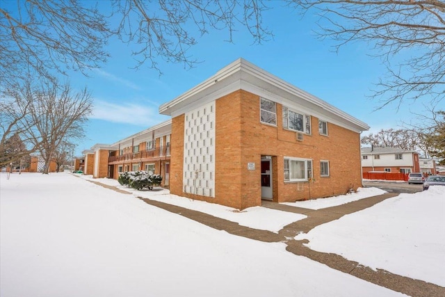 view of snow covered exterior with brick siding