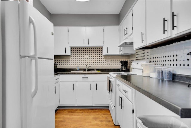 kitchen featuring white appliances, dark countertops, a sink, and white cabinets