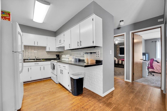 kitchen with dark countertops, white appliances, under cabinet range hood, and white cabinetry