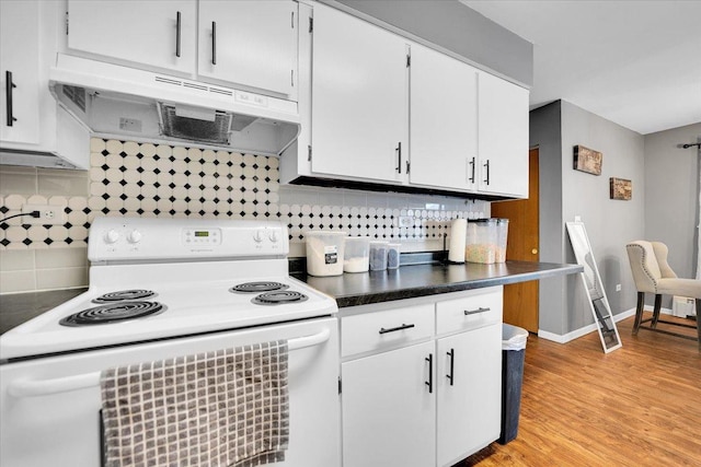 kitchen with white electric stove, dark countertops, backsplash, white cabinetry, and under cabinet range hood