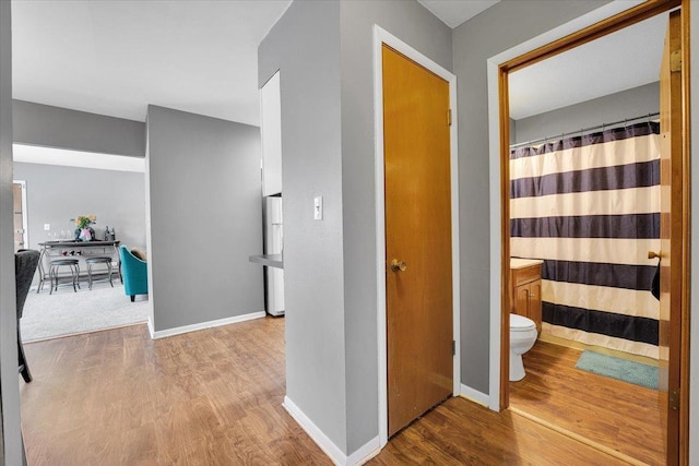 corridor with baseboards and wood finished floors