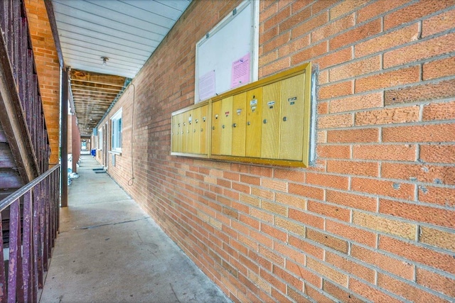 hallway with concrete flooring, brick wall, and mail area