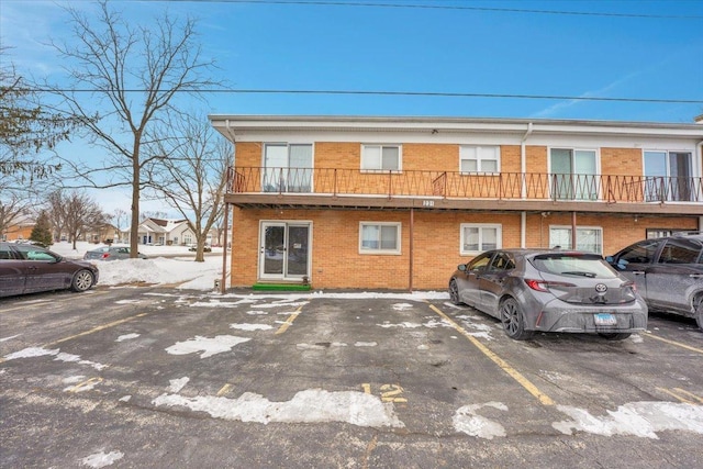 view of property with uncovered parking and brick siding