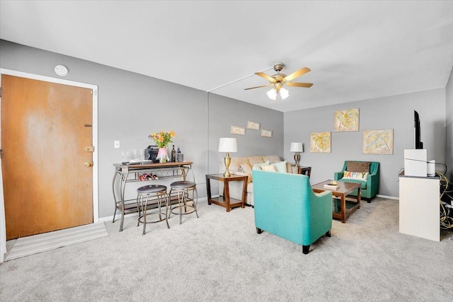 living area featuring light colored carpet, ceiling fan, and baseboards