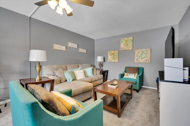 living area with a ceiling fan, light carpet, and baseboards