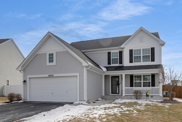 traditional-style home featuring aphalt driveway, roof with shingles, a porch, board and batten siding, and fence