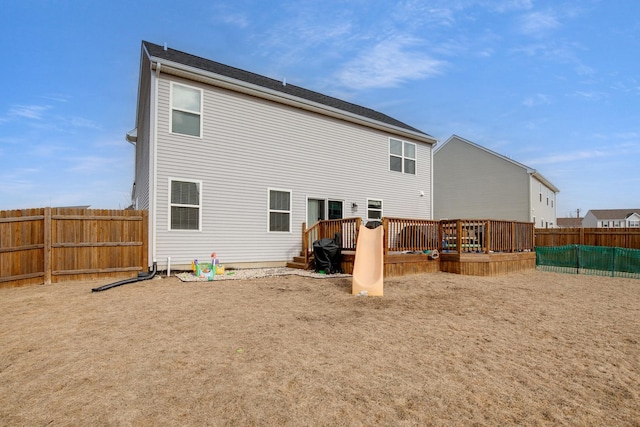 rear view of house with a fenced backyard and a deck