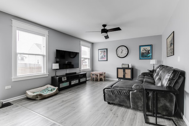 living area with wood finished floors, a ceiling fan, and baseboards