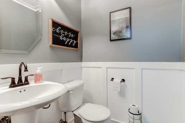 half bath featuring a wainscoted wall, a sink, and toilet