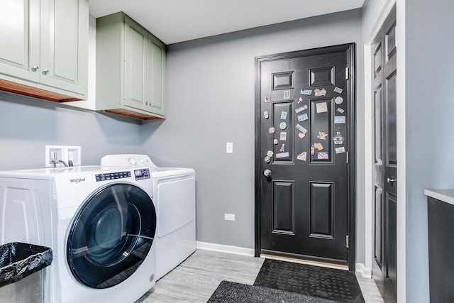 clothes washing area featuring light wood finished floors, washer and clothes dryer, cabinet space, and baseboards