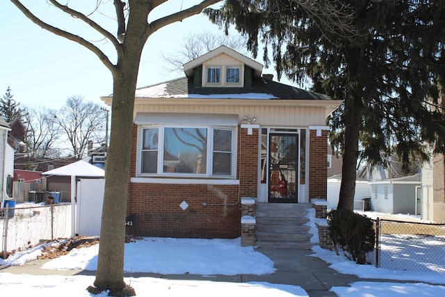 bungalow-style house featuring brick siding and fence