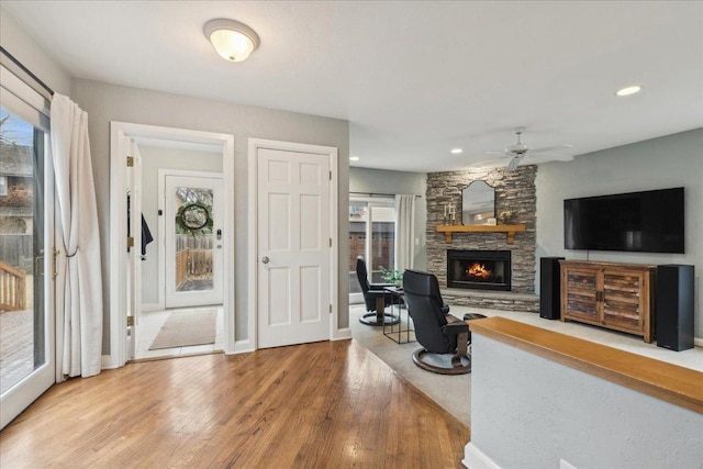 foyer entrance with a stone fireplace, recessed lighting, wood finished floors, a ceiling fan, and baseboards