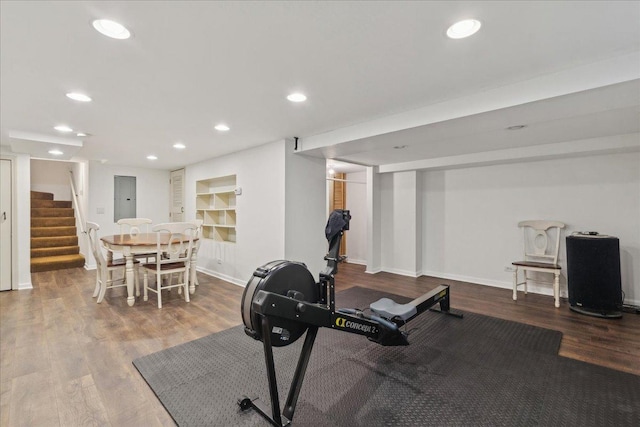 workout area featuring recessed lighting, electric panel, baseboards, and wood finished floors
