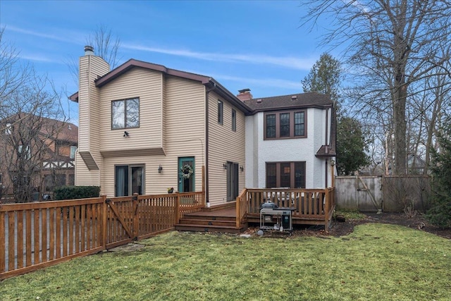 rear view of house with a deck, a chimney, fence, and a lawn