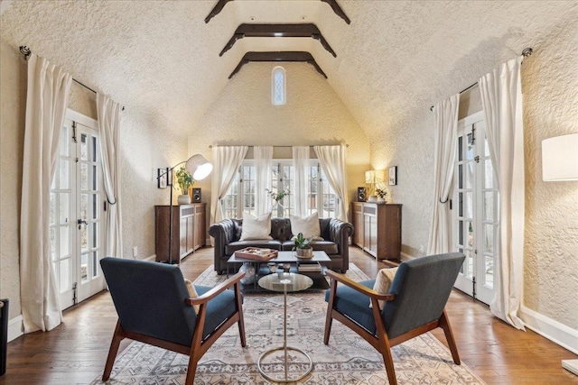living area with a textured wall, high vaulted ceiling, baseboards, french doors, and wood-type flooring