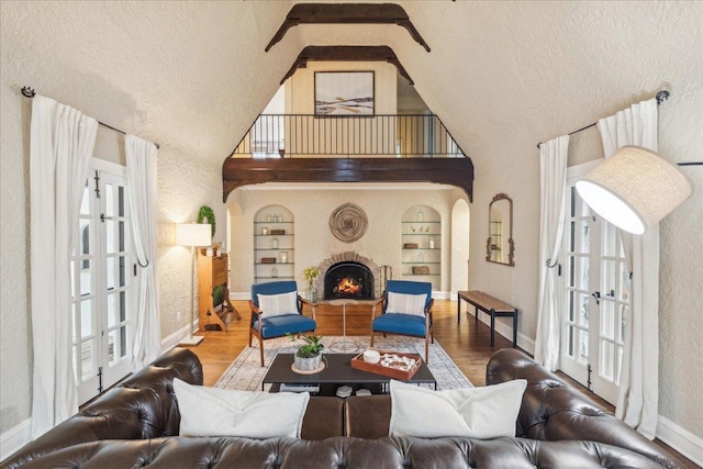 living area featuring baseboards, a fireplace, wood finished floors, and built in features
