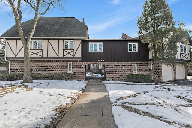 view of front of house featuring brick siding, an attached garage, a shingled roof, and aphalt driveway