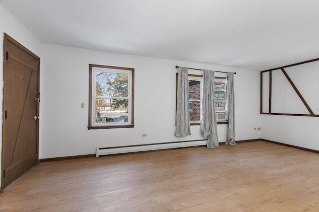 unfurnished room with light wood finished floors, plenty of natural light, a baseboard heating unit, and baseboards