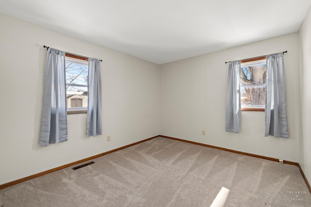 unfurnished room with a healthy amount of sunlight, baseboards, visible vents, and carpet flooring