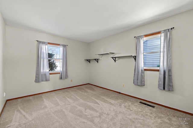 spare room featuring baseboards, visible vents, and light colored carpet