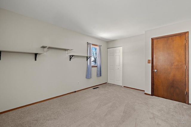 spare room featuring baseboards, visible vents, and light colored carpet