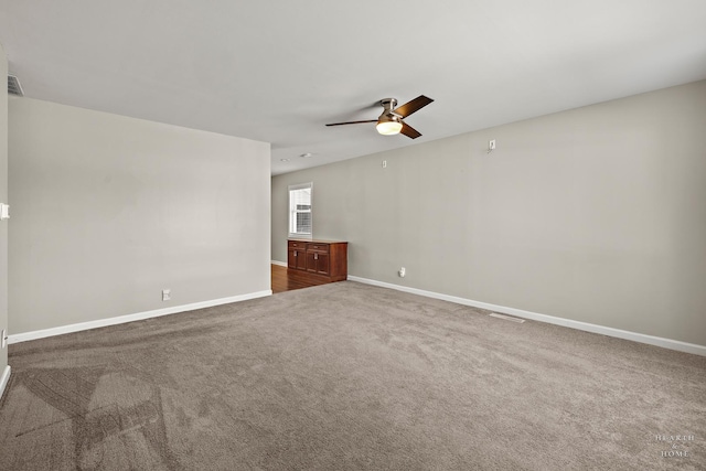 carpeted empty room with visible vents, ceiling fan, and baseboards