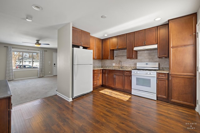 kitchen with light stone counters, open floor plan, a sink, white appliances, and under cabinet range hood