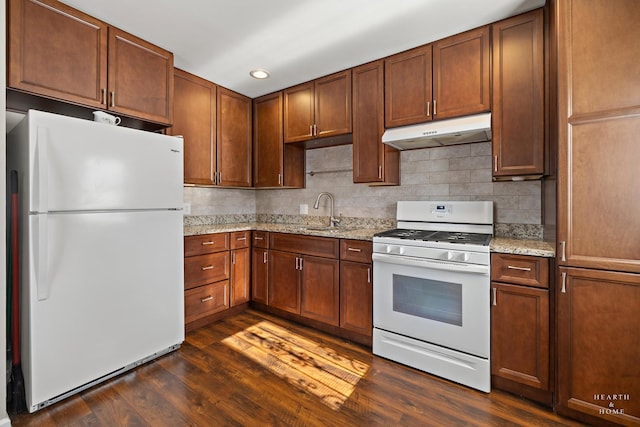 kitchen with dark wood-style floors, a sink, light stone countertops, white appliances, and under cabinet range hood