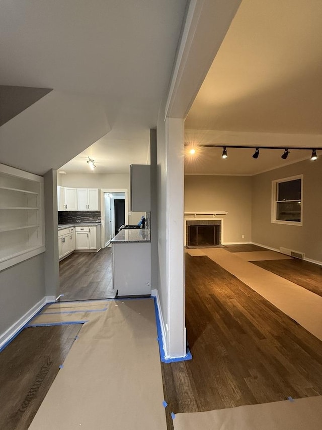 unfurnished living room with dark wood-style floors, visible vents, and baseboards