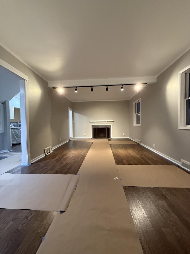 unfurnished living room with a fireplace, wood finished floors, visible vents, and baseboards