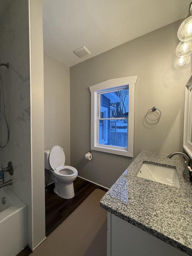 bathroom featuring toilet, wood finished floors, visible vents, vanity, and tub / shower combination