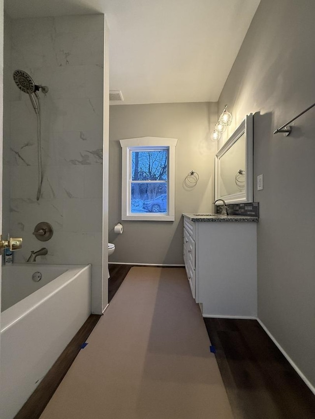 full bath with toilet, wood finished floors, visible vents, vanity, and shower / bathing tub combination