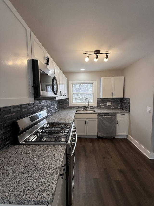 kitchen featuring dark wood-style floors, backsplash, appliances with stainless steel finishes, white cabinetry, and a sink