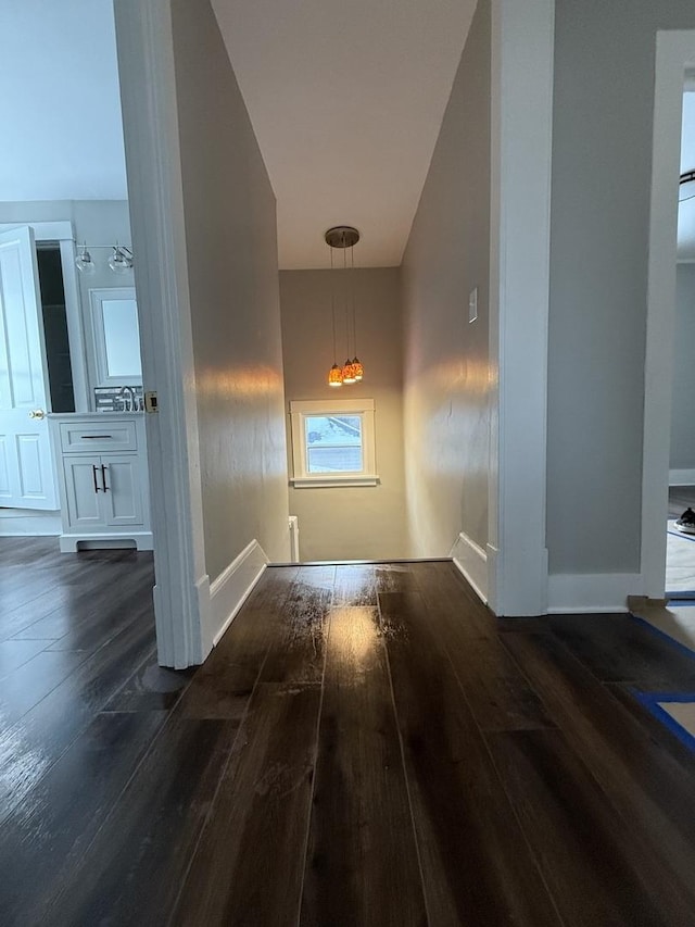 hallway with dark wood finished floors and baseboards