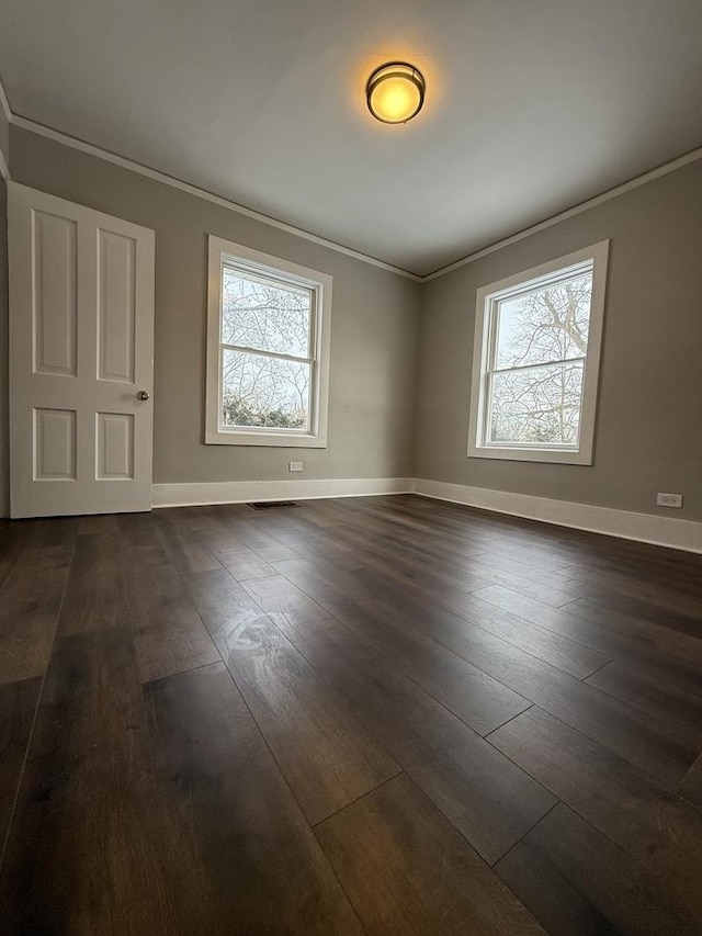 spare room featuring baseboards, visible vents, ornamental molding, and dark wood finished floors