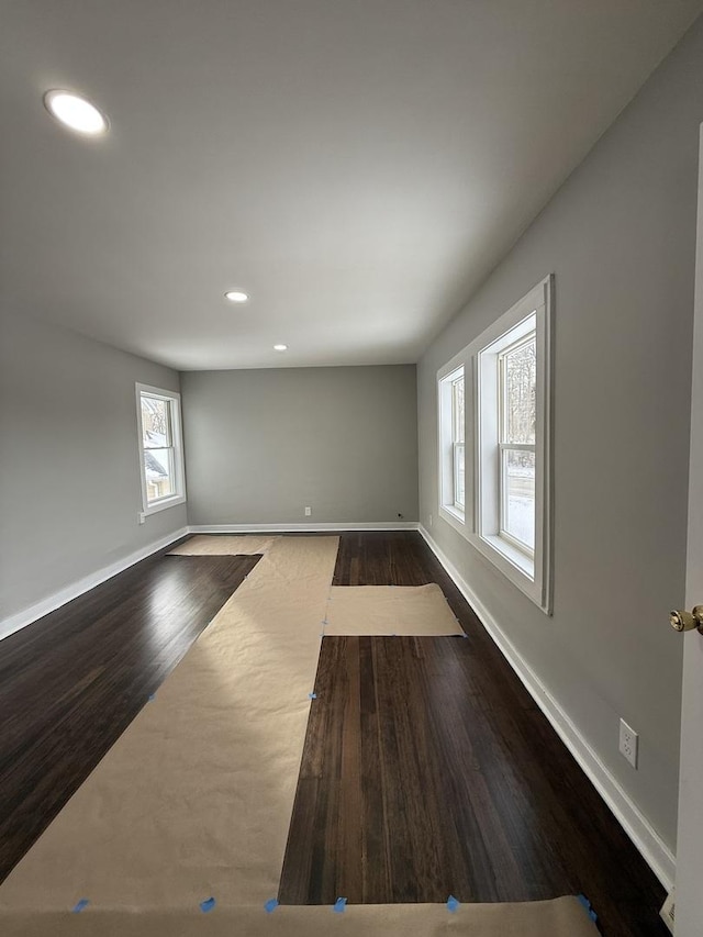 spare room featuring dark wood-type flooring, recessed lighting, and baseboards