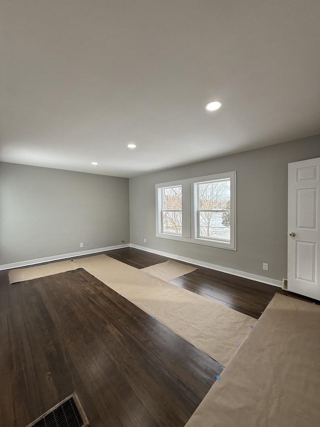 unfurnished living room featuring dark wood-type flooring, recessed lighting, and baseboards