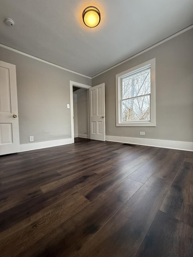 unfurnished bedroom featuring dark wood-style flooring, visible vents, crown molding, and baseboards