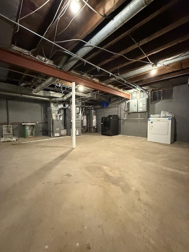 unfinished below grade area featuring gas water heater, electric panel, washer and clothes dryer, and heating unit