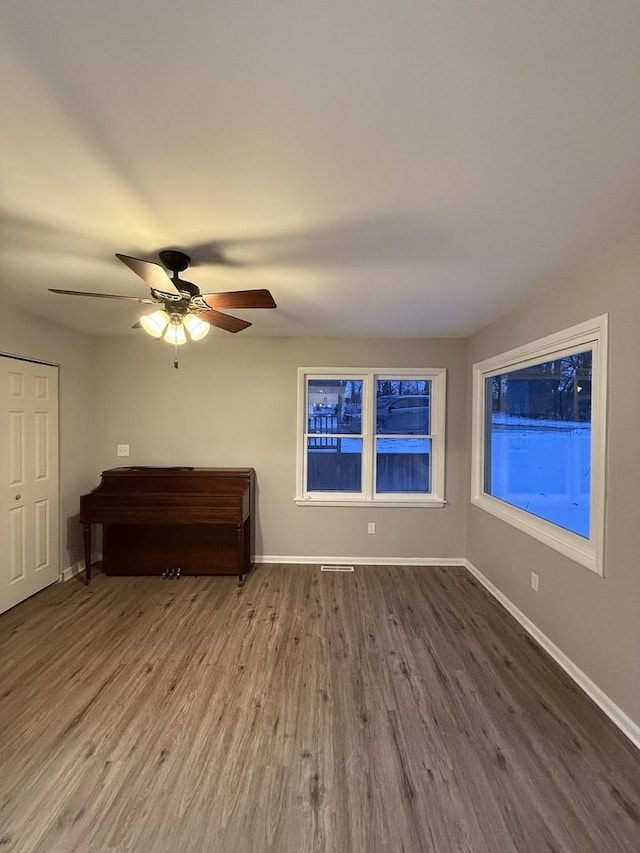 interior space featuring ceiling fan, wood finished floors, and baseboards