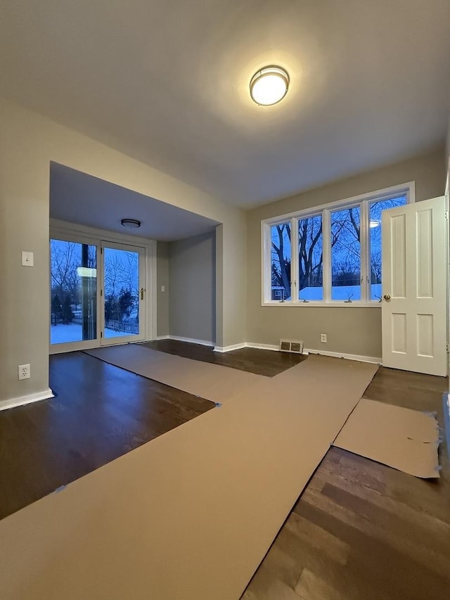 unfurnished living room featuring wood finished floors, visible vents, and baseboards