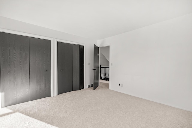 carpeted bedroom with visible vents and two closets