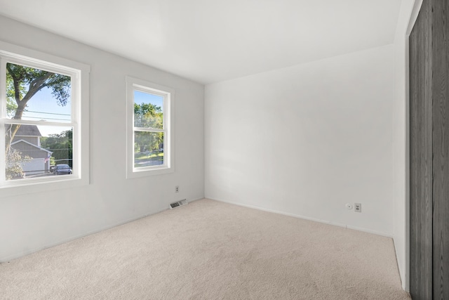 unfurnished room featuring light colored carpet and visible vents