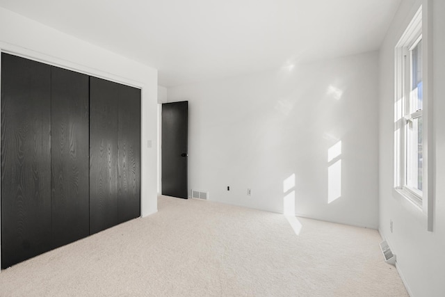 bedroom featuring light carpet, visible vents, and a closet