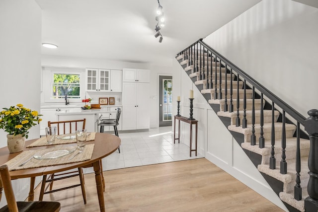 dining room featuring stairs, light wood finished floors, and track lighting