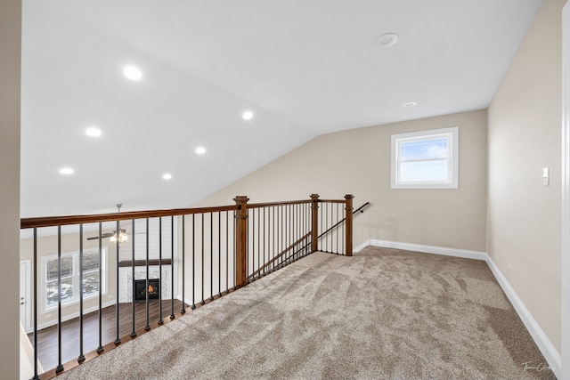 bonus room featuring baseboards, carpet, a lit fireplace, vaulted ceiling, and recessed lighting