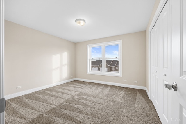 unfurnished bedroom featuring carpet, visible vents, baseboards, and a closet