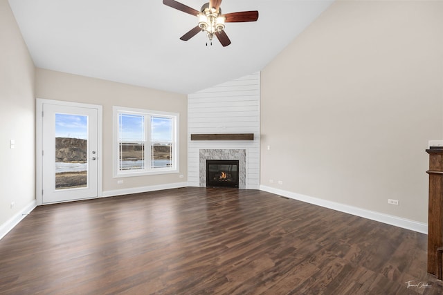 unfurnished living room with dark wood-style floors, lofted ceiling, a premium fireplace, ceiling fan, and baseboards