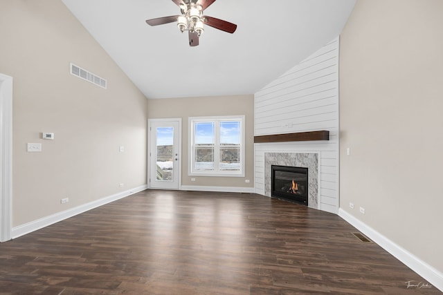 unfurnished living room with high vaulted ceiling, a premium fireplace, visible vents, baseboards, and dark wood-style floors