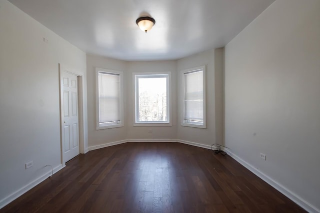 unfurnished room featuring dark wood-style floors and baseboards